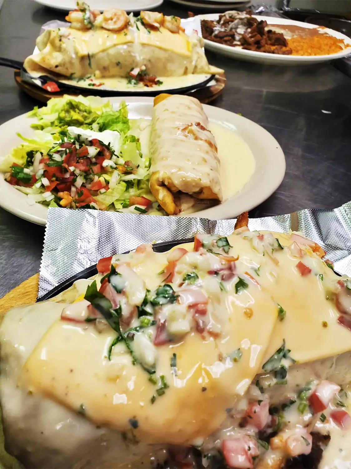 A colorful collage featuring a grilled chicken wrap, a burrito, and a salad with fresh herbs, lettuce, and sliced tomatoes.