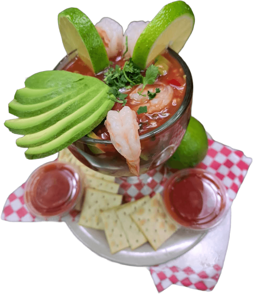 A bowl of shrimp and avocado served with crackers and dipping sauce on a wooden table.